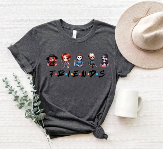 Gray t-shirt with cartoon character design and 'FRIENDS' text, placed on a white surface with a hat and plant.